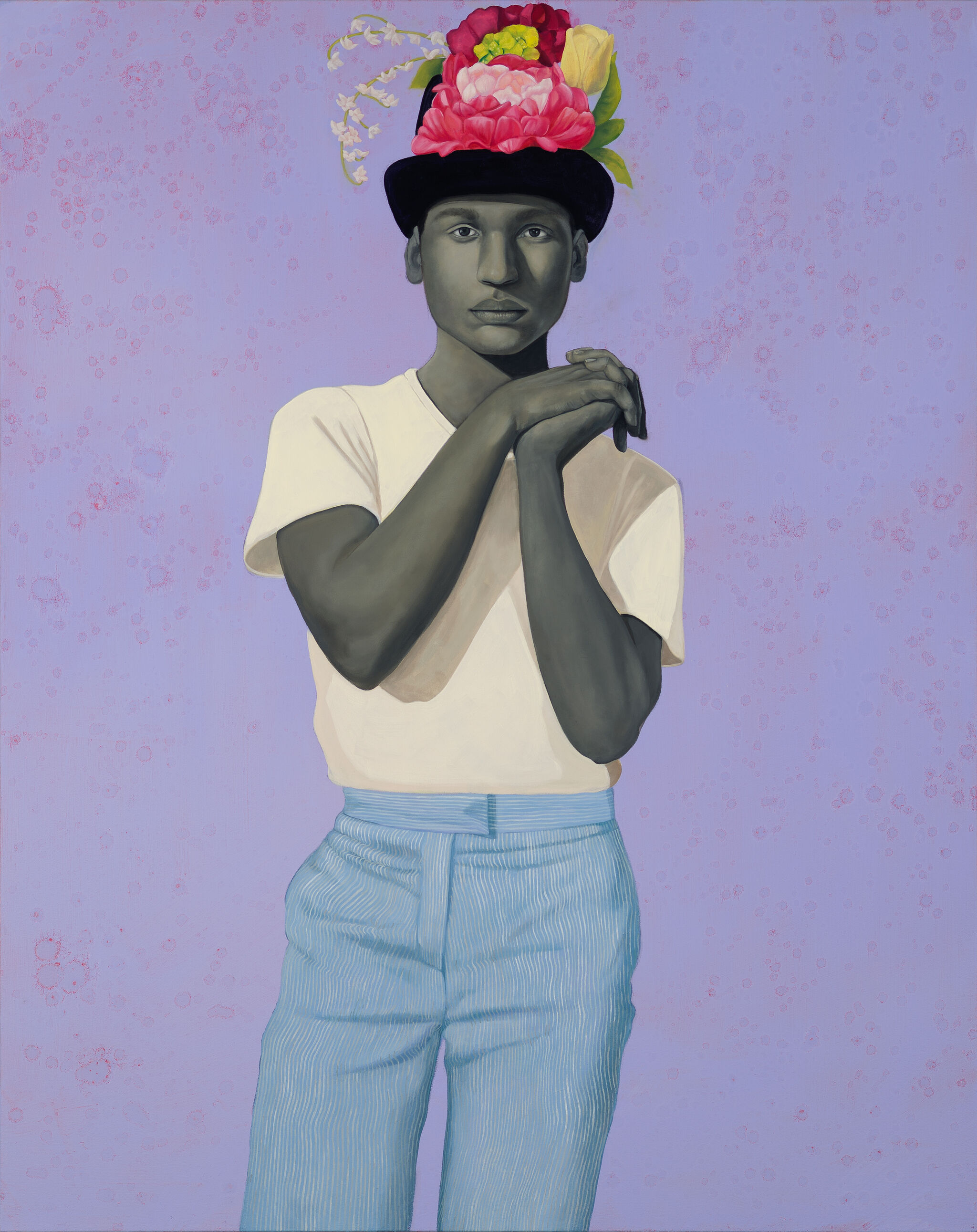 Person in a white shirt and blue pants, wearing a black hat adorned with vibrant flowers, set against a purple background.
